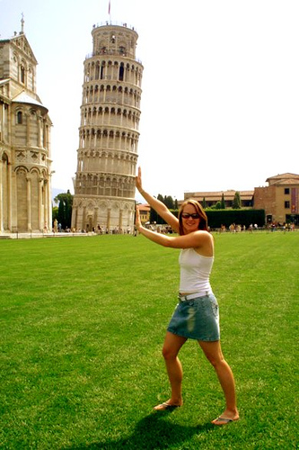 Photograph of a woman appearing to be holding up the leaning tower of Piza