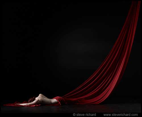 Fine Art Photographer Steve Richard's image showing a nude tastefully draped in sheet of very long dark red fabric.