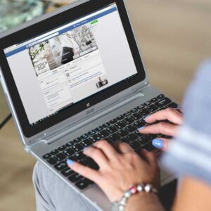 a woman holding a laptop computer on her lap with a social media site being displayed on the screen